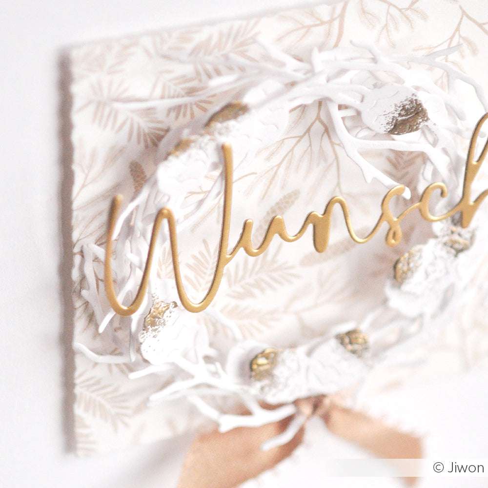 Eleganter weißer Kranz mit goldenem "Wunsch"-Text von Alexandra Renke auf gemustertem Designpapier, akzentuiert mit Tannenzweig Dunkelbeige und gold-weißem Band - ideal für stilvolle Papierprojekte.