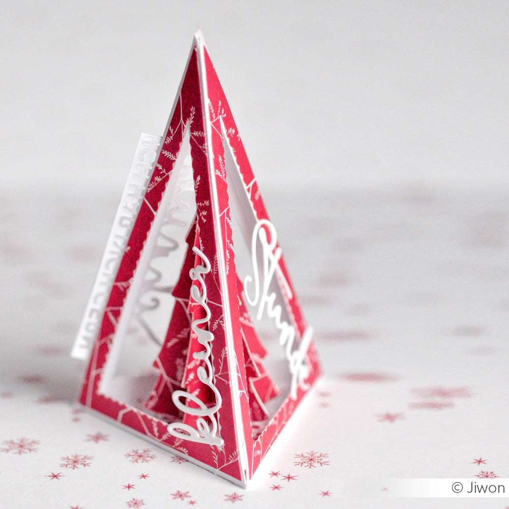 Eine rot-weiße Papierpyramide aus Alexandra Renke Designpapier mit ausgeschnittenen Wörtern auf einer weißen Oberfläche mit Schneeflocken-Muster. Ideal für festliche Papierprojekte!.