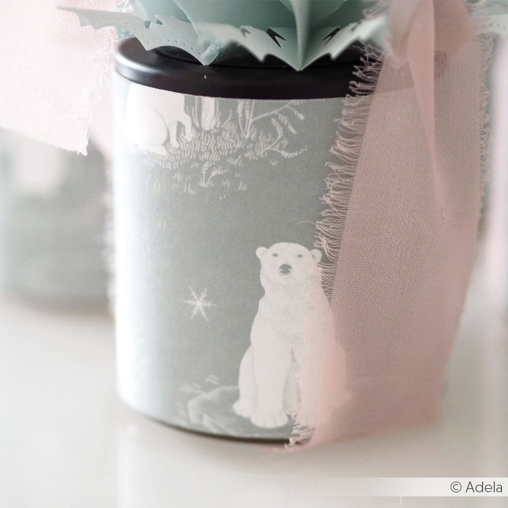 Ein hellblauer Behälter von Alexandra Renke mit einer weißen Illustration von Eisbär und Freunde, gebunden mit einem rosafarbenen durchsichtigen Band.