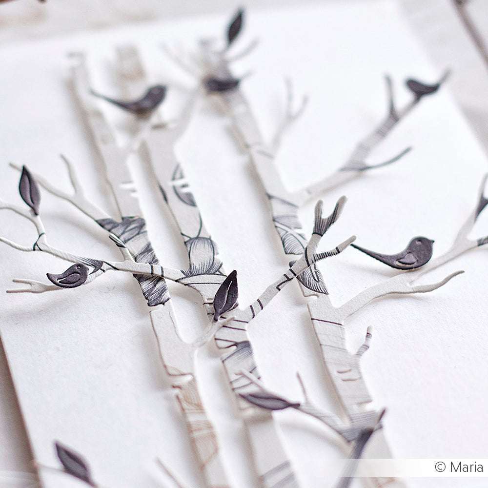 Papierausschnitt von Birken mit kleinen schwarzen Vögeln auf den Ästen, hergestellt aus hochwertigem Alexandra Renke Designpapier, vor weißem Hintergrund - perfekt für Papierprojekte oder Buchbinderei.