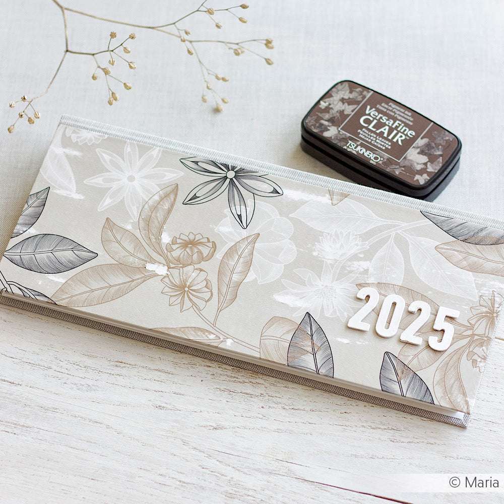 Auf einer weißen Fläche mit getrockneten Stängeln ruhen ein Blumenplaner 2025 und ein Stempelkissen von Alexandra Renke - ideal für Papierprojekte oder in Kombination mit den Designpapieren Anis Floral und Würzig Greige.