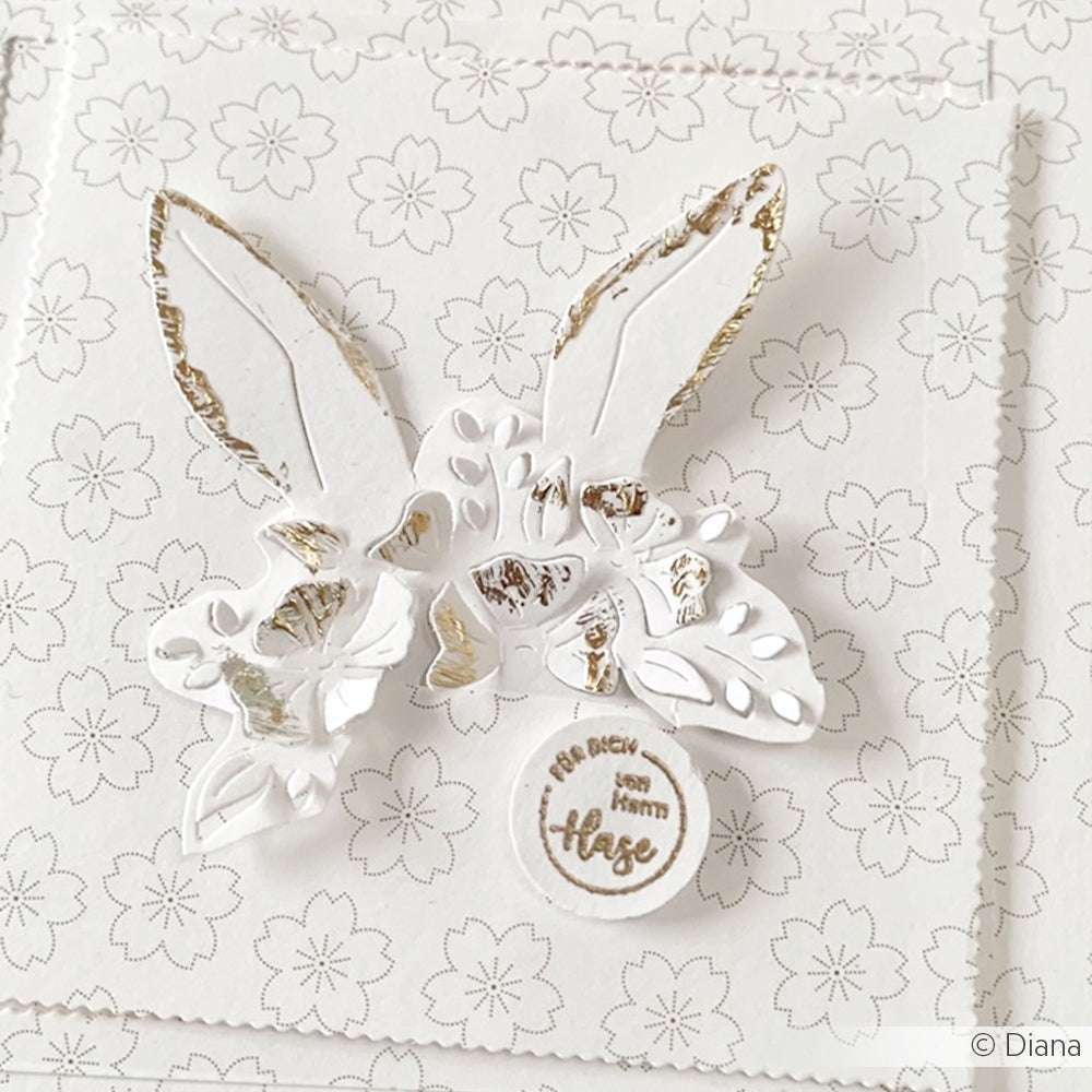 Weiße Blumenkarte mit goldenen Hasenohren auf dezentem Kirschblütenhintergrund - perfekt für Papierprojekte oder als elegantes Designpapier, im zarten Blüten-Gold-Outline-Stil von Alexandra Renke.