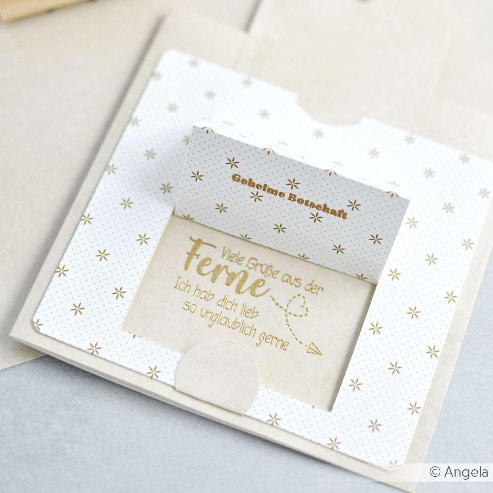 Grußkarte von Alexandra Renke mit deutschem Text in Gold auf gepunktetem Designpapier, teilweise aus einem dekorativen Umschlag gezogen - ideal für kreative Projekte und persönliche Grußkarten.