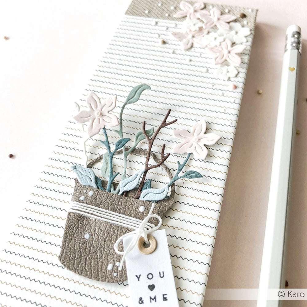 Ein dekoriertes Notizbuch von Alexandra Renke mit floralen Motiven auf hochwertigem Designpapier und einem "You & Me"-Anhänger, der neben einem weißen Bleistift liegt.