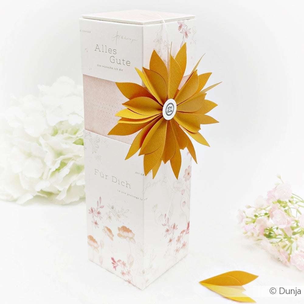 Elegante, hohe, florale Geschenkbox von Alexandra Renke, hergestellt mit Designpapier. Mit einer großen orangefarbenen Papierblume, umgeben von weißen und rosafarbenen Blüten - eine atemberaubende Blumenpost für jeden besonderen Anlass.