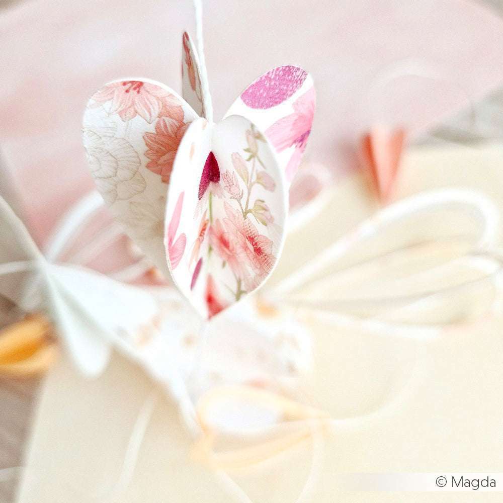 Herzförmiges Ornament aus Alexandra Renke Designpapier mit zarten floralen Mustern, akzentuiert durch zarte pastellfarbene Bänder und einen verschwommenen Hintergrund - ideal für Grußkarten oder kreative Papierprojekte.