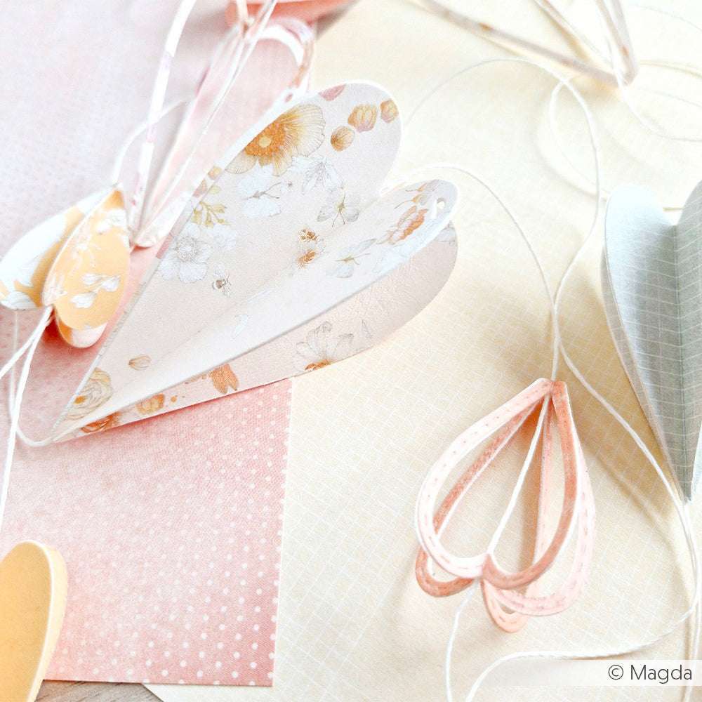 Pastellfarbene Papierherzen liegen auf einer hellen Fläche mit gemusterten Alexandra Renke Designpapierbögen, die sich perfekt für Papierprojekte eignen oder einen Hauch von Blumendesign-Charme versprühen.