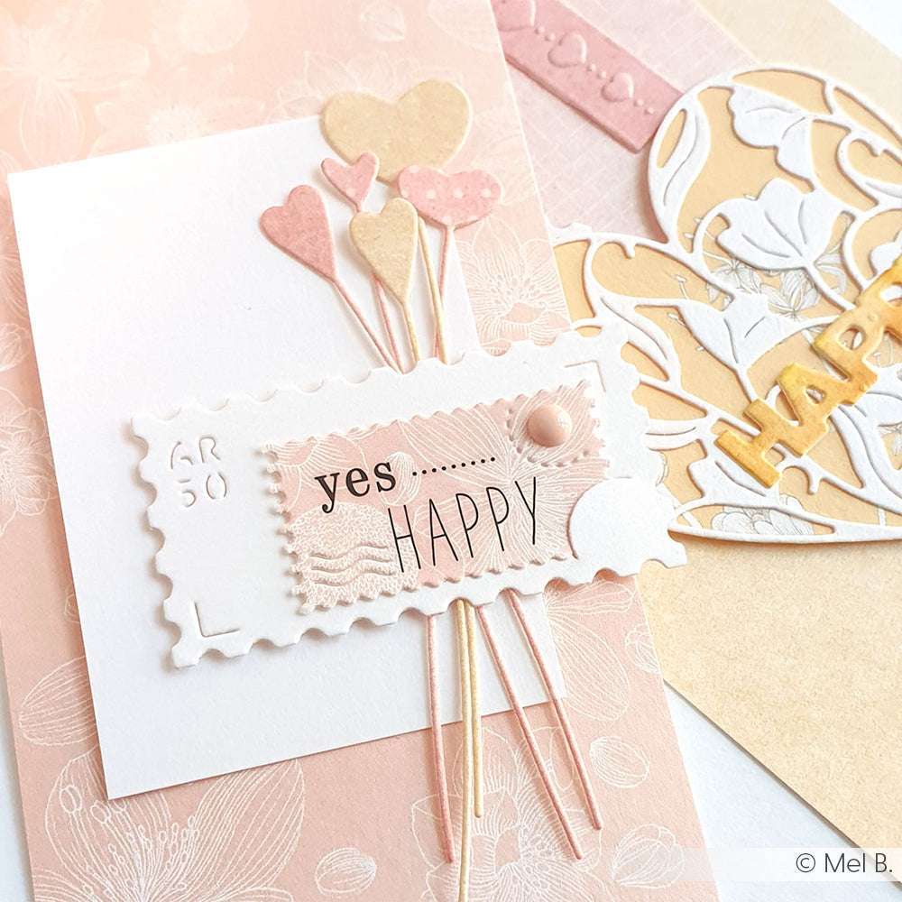 Eine handgemachte Karte mit pastellfarbenen Herzen, einem "yes... HAPPY"-Schriftzug und zarten Blumen- und Herzmotiven ist mit Alexandra Renke Designpapier und weißen Outlineblüten besonders charmant gestaltet.