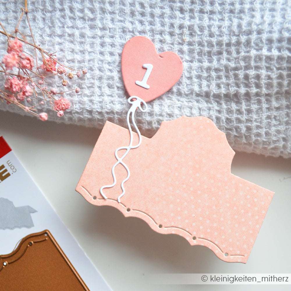 Rosa gepunktete Karte mit einem herzförmigen Ballon mit der Aufschrift 1, hergestellt mit hochwertigem Designpapier von Alexandra Renke, präsentiert auf strukturiertem weißem Stoff - die perfekte Inspiration für Ihre nächsten Papierprojekte.