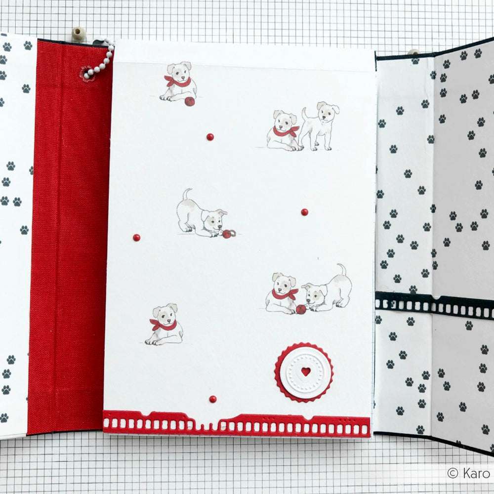 Weiße Karte von Alexandra Renke mit kleinen Welpen-Illustrationen, roten Akzenten und Pfotenabdrücken - perfekt als Designpapier für Papierprojekte oder als charmantes Accessoire für jedes kreative Projekt.