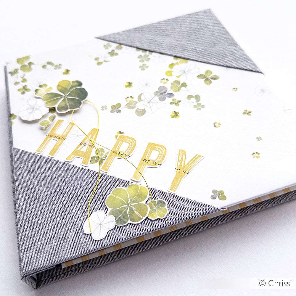Alexandra Renke Grußkarte mit Glücksklee Designpapier, dem Wort "HAPPY" in Gold und grauen Stoffecken.