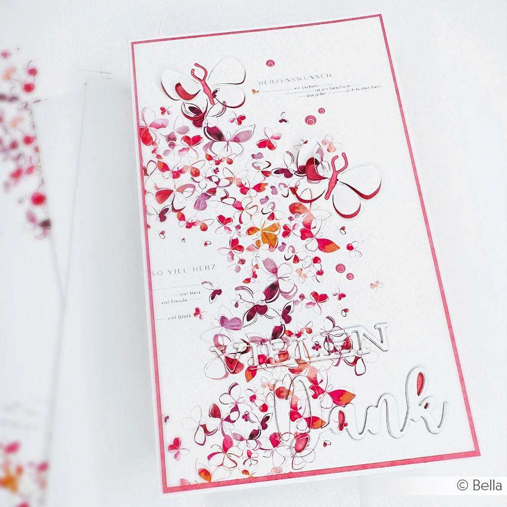 Eine Grußkarte von Alexandra Renke mit rosa und lila Schmetterlingen aus Bastelpapier und "Dank" in silberner Schrift auf der Vorderseite.
