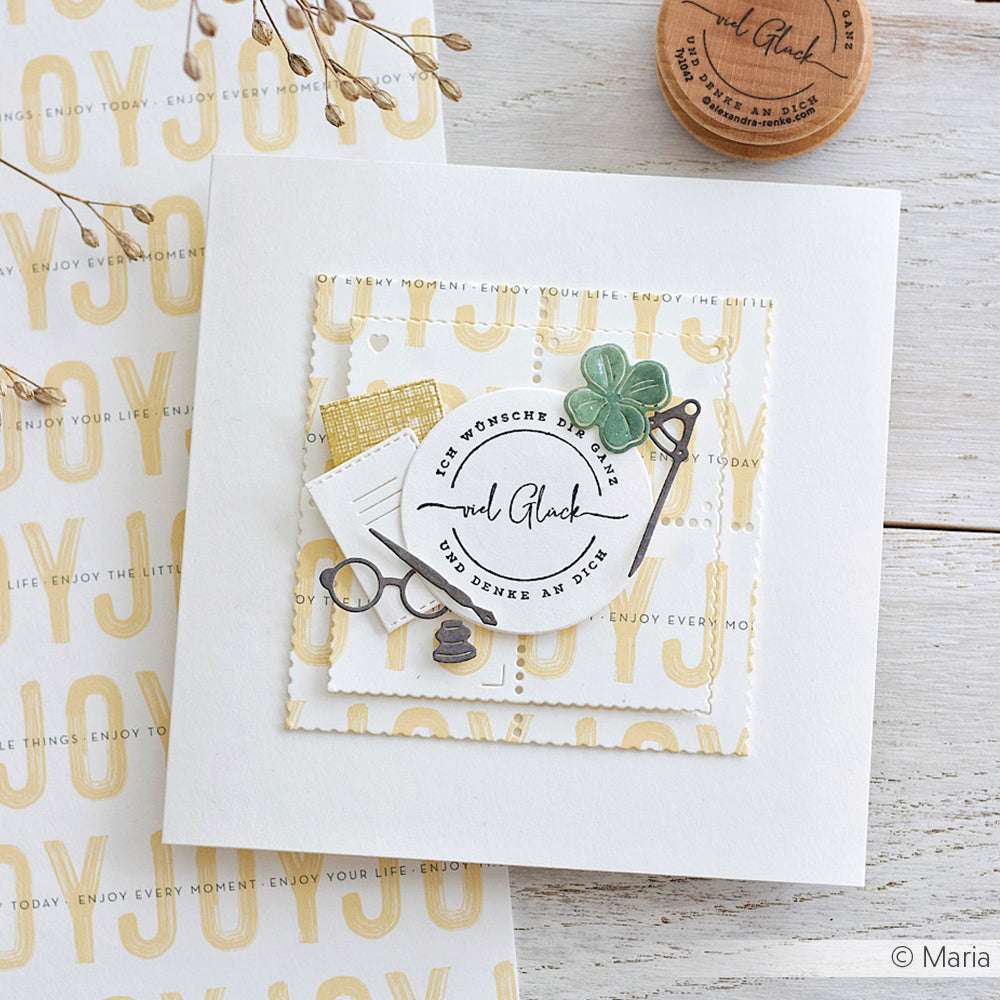 Handgefertigte Grußkarte von Alexandra Renke mit deutschem Text, Kleeblatt, Brille und Stiften auf weiß-gelb gemustertem Hintergrund - perfekt für Papierprojekte oder um mit einzigartigem Designpapier eine besondere Note zu verleihen.