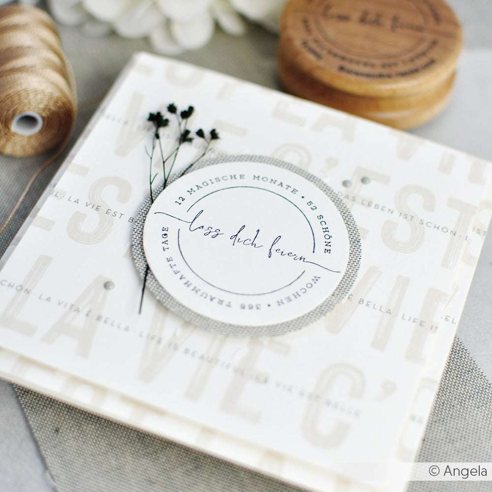 Elegante Grußkarte von Alexandra Renke, gestaltet mit neutralem Designpapier, mit getrockneten Blumen und deutschem Text auf einem weichen, gemusterten Hintergrund.