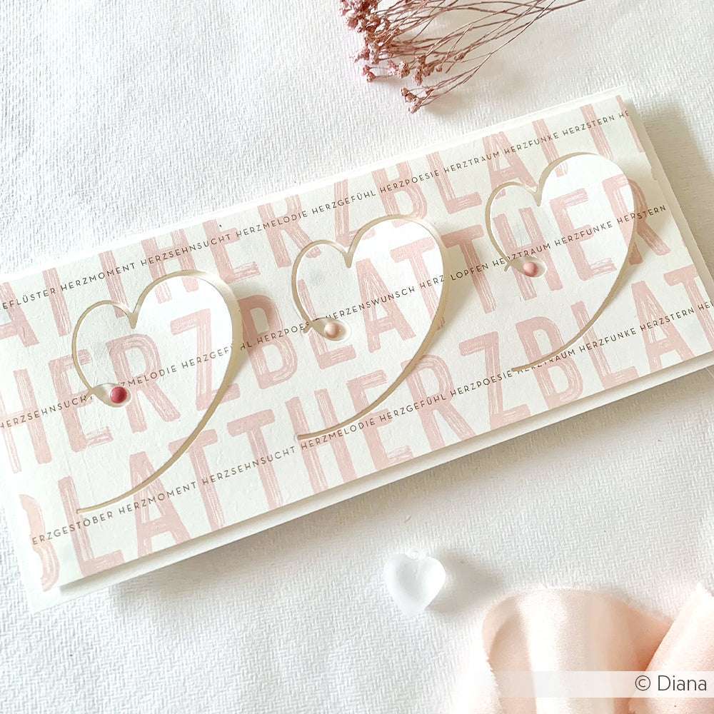 Handgemachte Karte von Alexandra Renke mit drei Herzausschnitten, zartrosa Text und kleinen Perlen - wunderschön gestaltet für Ihre Papierprojekte oder als Inspiration für Buchbinderei-Kreationen.
