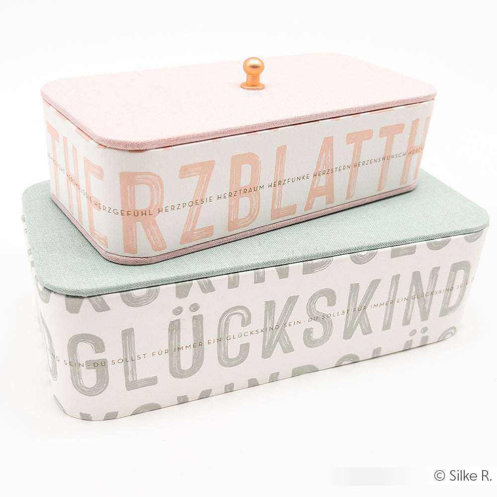 Zwei dekorative rechteckige Schachteln von Alexandra Renke, eine rosafarbene auf einer grünen gestapelt, mit Designpapier und deutschen Wörtern - perfekt zum Buchbinden oder für Papierprojekte.