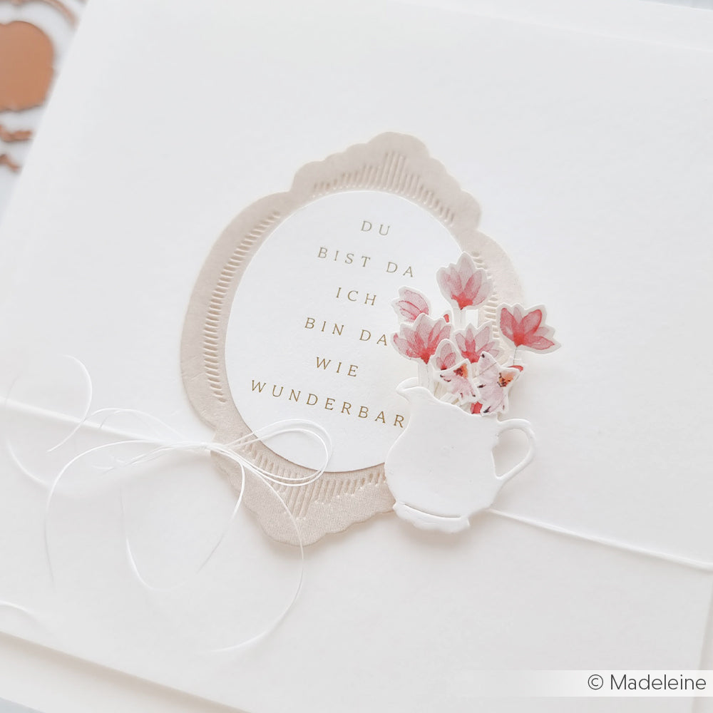 Eine zarte Karte von Alexandra Renke mit deutschem Text, die eine weiße Teekanne mit zarten Blütensträuße rosa und einer weißen Schleife zeigt - ideal für Papierprojekte oder zum Ausstellen Ihres Lieblingsdesignpapiers.