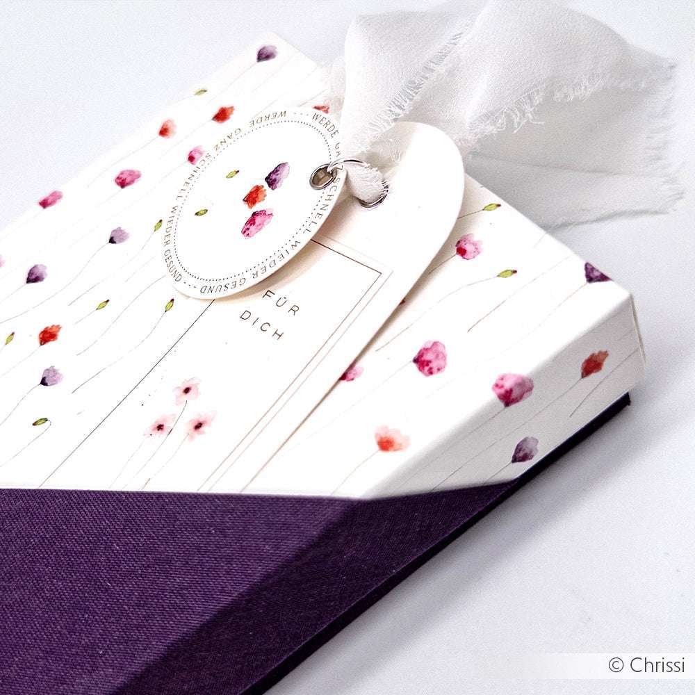 Rechteckige, geblümte Geschenkbox mit weißem Anhänger und durchsichtigem Band, teilweise umwickelt mit dem lila Designpapier Feine Mohnblüten von Alexandra Renke - ideal für exquisite Papierprojekte oder Buchbinderei-Kreationen.
