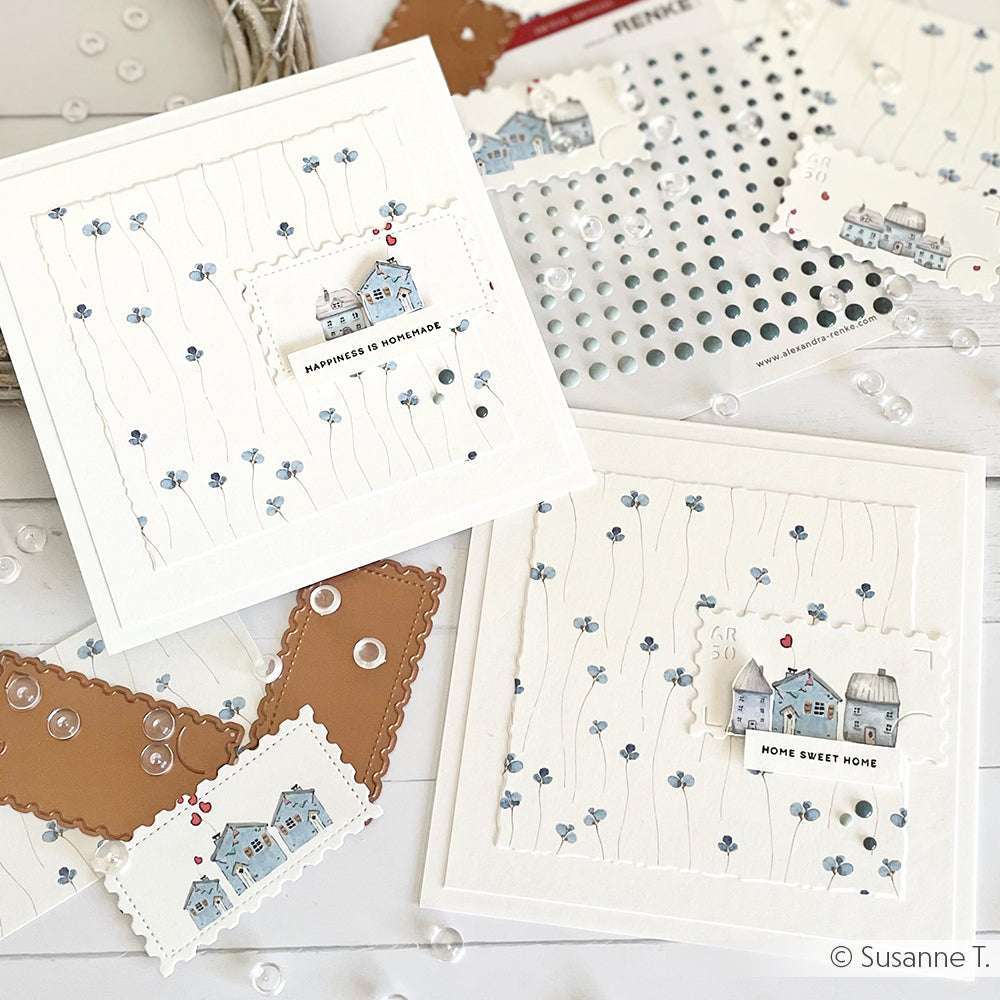 Zwei handgefertigte Alexandra Renke-Grußkarten mit kleinen Hausmotiven und blauen Blumen, beschriftet mit "Happiness is Homemade" und "Home Sweet Home" - perfekt für Ihre Papierprojekte.