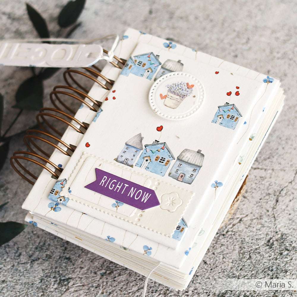 Ein spiralgebundenes Journal von Alexandra Renke im Design der Zarte Häuserreihe blau, mit charmanten Haus-Illustrationen, floralen Akzenten und einem RIGHT NOW-Etikett - ideal für Designpapier-Fans und Liebhaber von Papierprojekten.