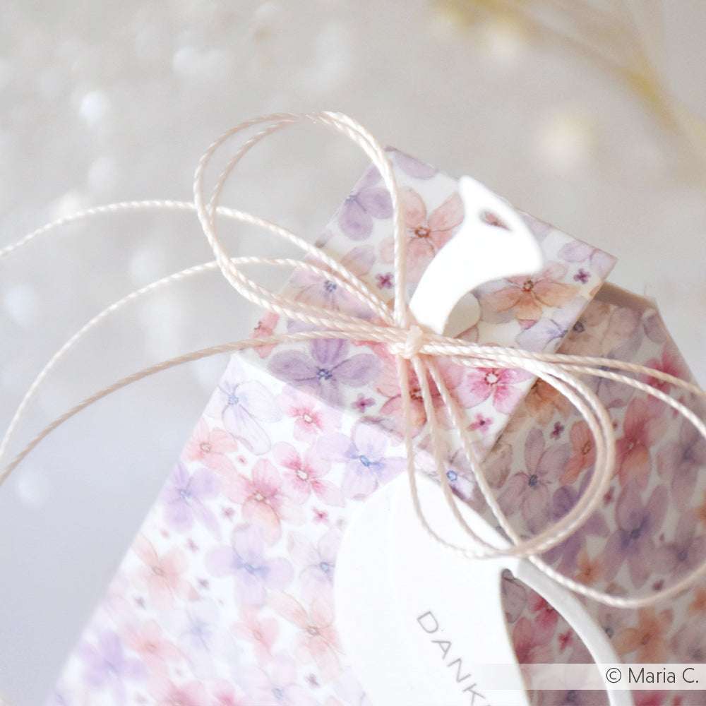 Alexandra Renke Geschenkbox mit lila-rosafarbenem, floralem Designpapier, verschnürt mit Schnur und einem weißen "DANK"-Anhänger - ideal für Ihr nächstes Papierbastelprojekt.