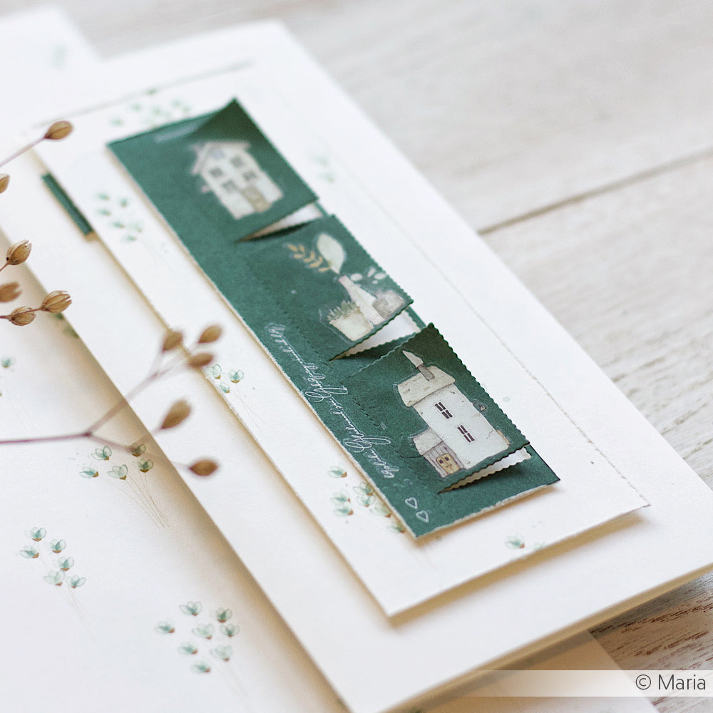 Eine handgefertigte Karte von Alexandra Renke zeigt einen grünen Streifen Designpapier mit kleinen Hausillustrationen und Zarte Blumensträuße in Minze, präsentiert auf einer weißen Holzoberfläche.