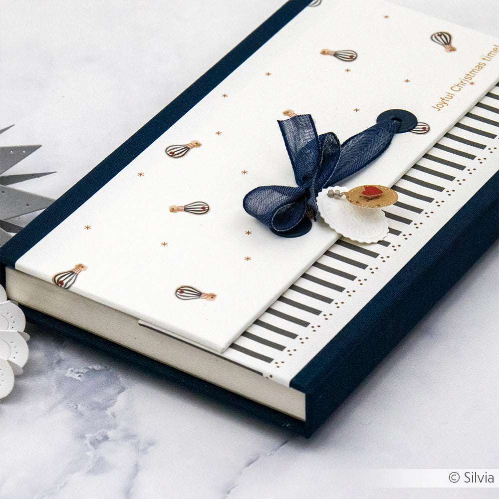 Elegante Geschenkbox von Alexandra Renke, verziert mit Schleife und Herzanhänger, im Klaviertasten-Design und Heißluftballon-Gewusel auf hochwertigem Designpapier - ideal für Ihre nächsten Papierprojekte.