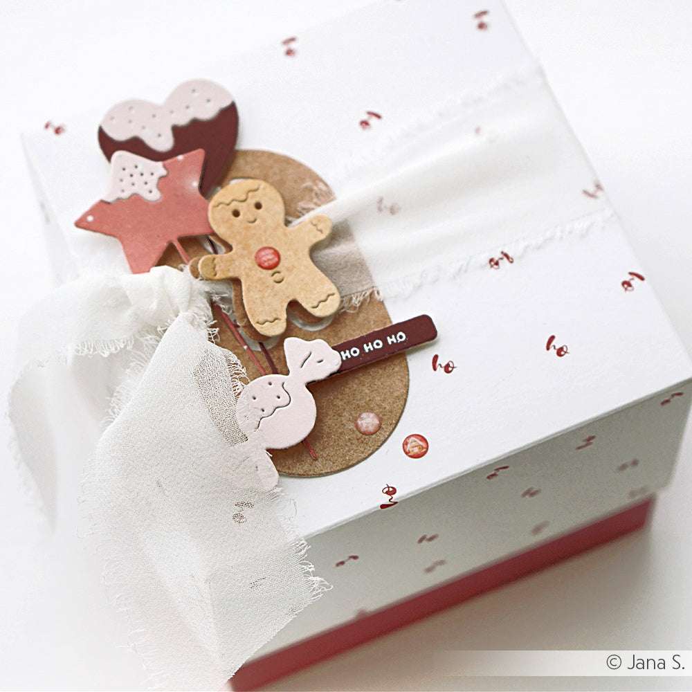 Weiße Geschenkschachtel von Alexandra Renke mit festlicher Keksdekoration, Schleife, Ho-Ho-Ho-Anhänger und einem Hauch von Designpapier-Charme auf weißem Hintergrund.