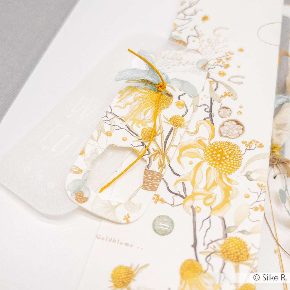 Nahaufnahme einer Grußkarte von Alexandra Renke mit gelben Blumen, Schleife und geprägter weißer Schrift - ein elegantes Designpapier, ideal für Papierprojekte.