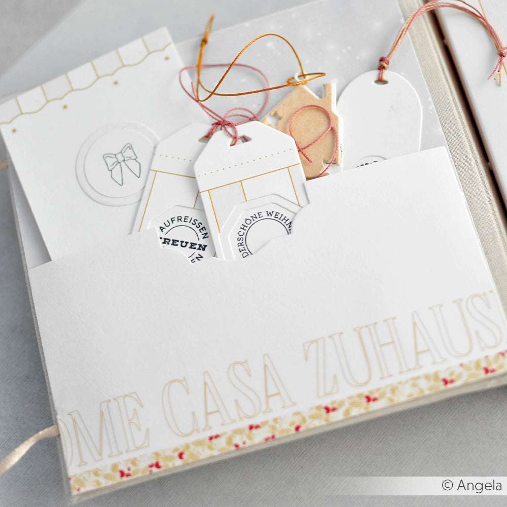 Weißer Umschlag mit Anhängern, Karten und Schnur von Alexandra Renke, beschriftet mit ME CASA ZUHAUS auf einem verzierten Designpapier-Hintergrund - ideal für Papierprojekte oder Buchbinderei.