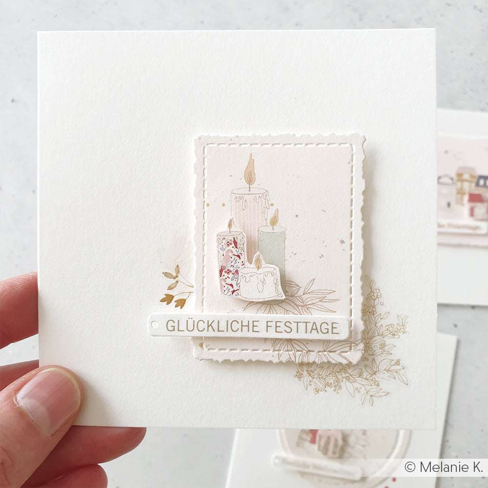 Hand hält eine Karte mit gemusterten Kerzen und dem Text GLÜCKLICHE FESTTAGE; ideal für Papierprojekte mit Alexandra Renke Designpapier.