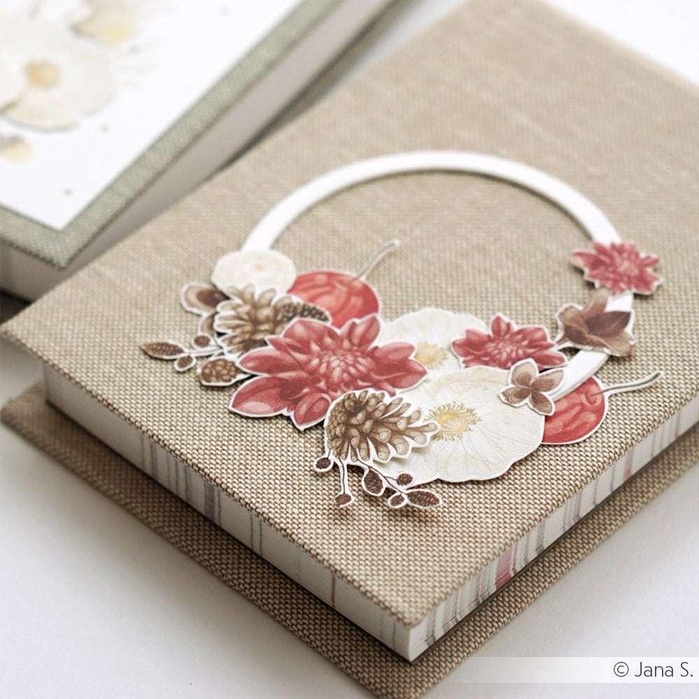 Handgefertigte Grußkarten von Alexandra Renke mit roten und weißen 3D-Blumen auf einem beigen Stoffbezug mit hochwertigem Designpapier, präsentiert in einer passenden Schachtel.