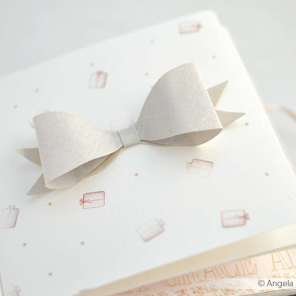 Eine cremefarbene Strukturschleife ziert eine weiße Karte von Alexandra Renke, die mit kleinen Geschenkillustrationen verziert ist - ideal für Papierprojekte oder zur Kombination mit Ihren Lieblingsdesignpapieren.