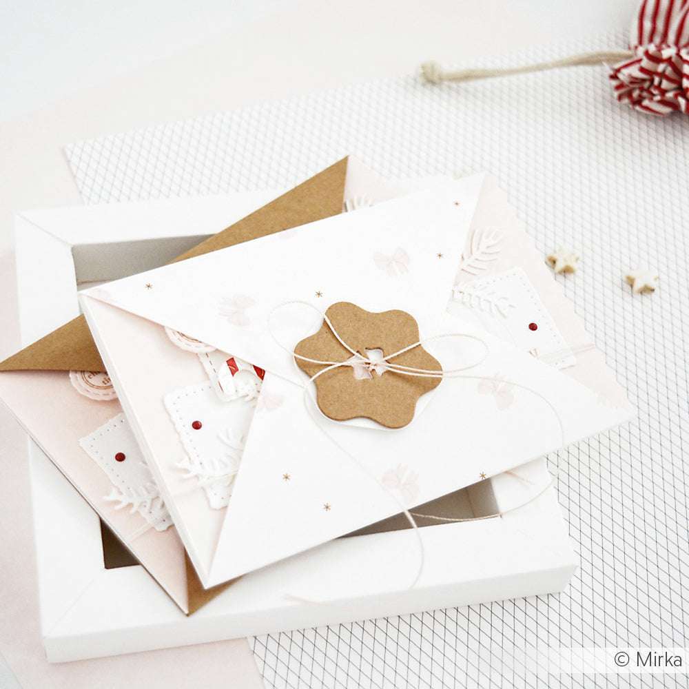 Zwei verzierte Briefumschläge, die mit einer Schnur zusammengebunden sind, ruhen auf einer weißen Schachtel auf Rasterpapier - ideal für Papierprojekte oder zum Kombinieren mit Ihren Lieblingsgrußkarten, die alle aus hochwertigem Alexandra Renke Designpapier hergestellt wurden.