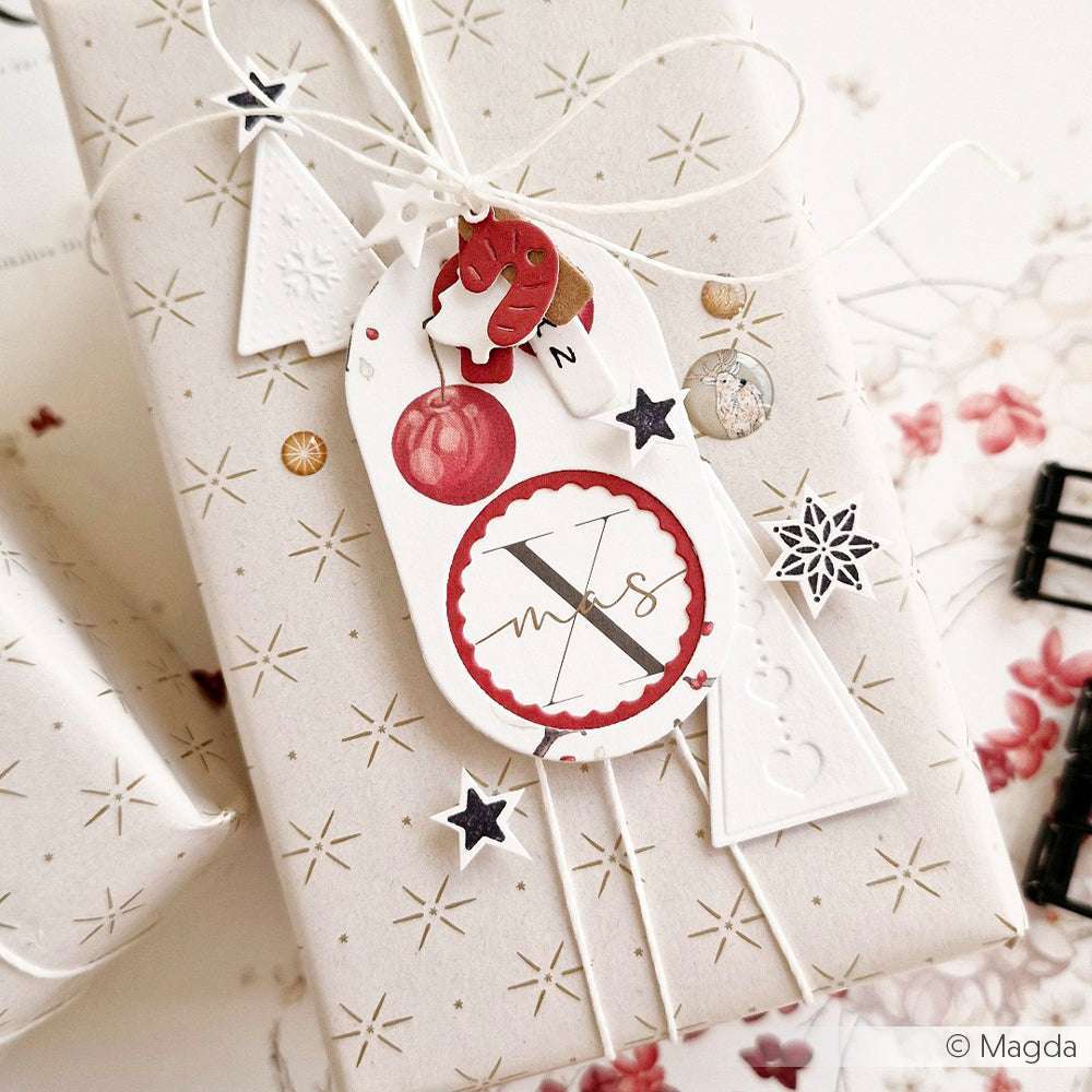 Als Geschenk verpackt in Alexandra Renkes sternförmigem Designpapier mit festlichen Anhängern, Kordel und weihnachtlicher Dekoration - ideal für Papierprojekte oder Buchbinderei-Charme.