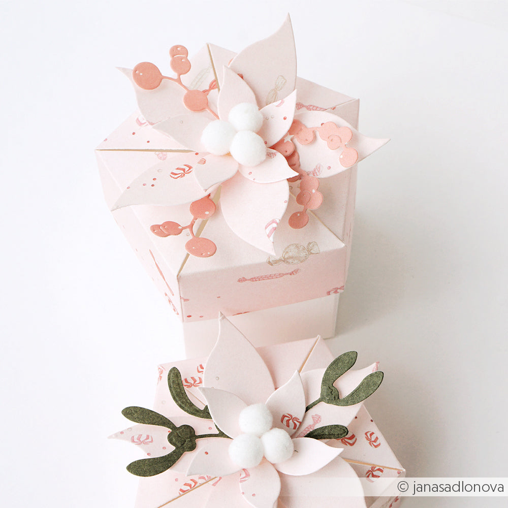 Zwei hellrosa sechseckige Geschenkboxen mit Papierblumen und weißen Pompons für Designpapier.