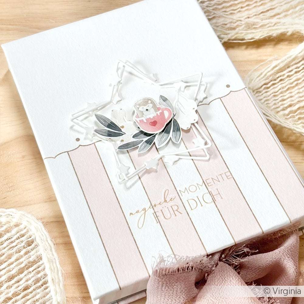 Handgefertigte Karte von Alexandra Renke mit einem Stern, Blättern, einem Igel mit Herz und dem Text "magische Momente für dich". Verziert mit Designerpapier und rosafarbener gestreifter Pünktchenborte - ideal für besondere Papierprojekte!.