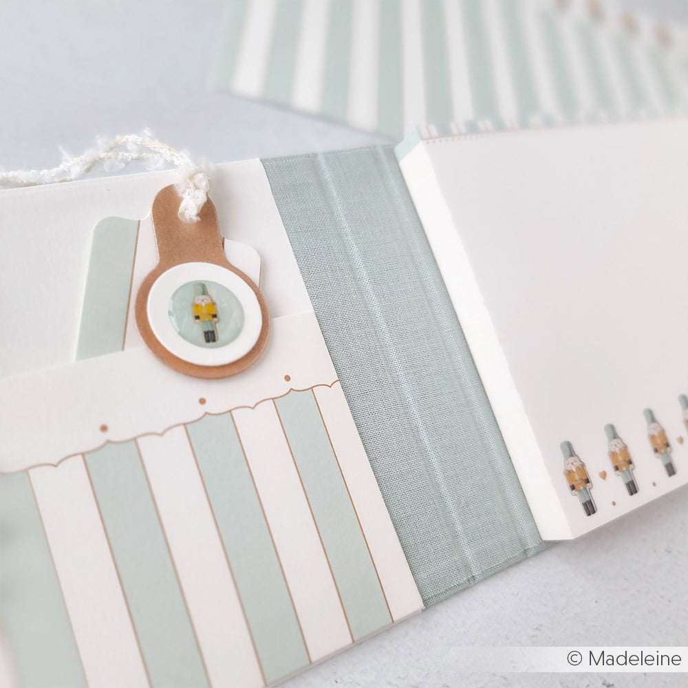 Alexandra Renke pastellfarbenes Notizbuch mit gestreiften Taschen, Nussknacker-Details, einem runden Nussknacker-Anhänger und mintfarbener Pünktchen-Bordüre mit Streifen - ideal für Papierprojekte oder zum Hinzufügen Ihres Lieblingsdesignpapiers.