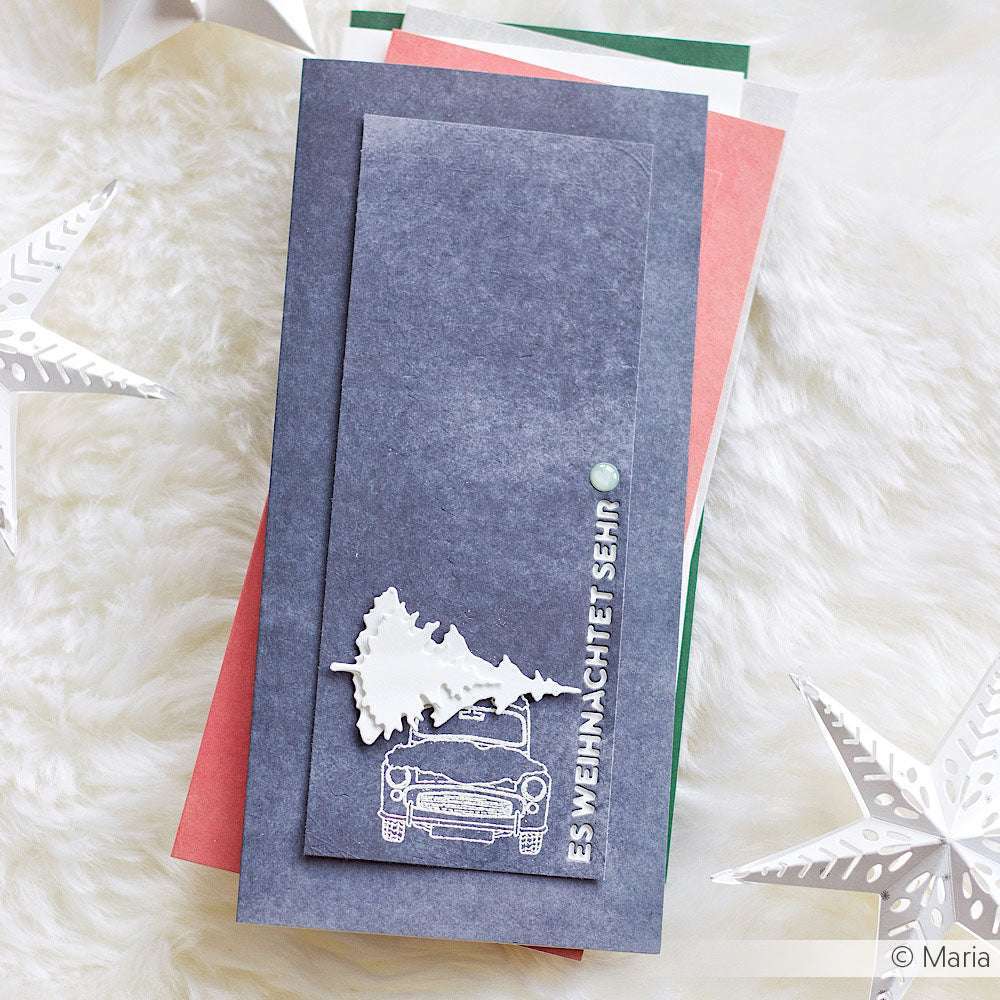 Handgemachte Weihnachtskarte von Mimi Schwarzwaldblau mit Auto- und Baummotiv, deutschem Text und Papiersternen auf flauschig weißer Oberfläche. Hergestellt mit hochwertigem Designpapier von Alexandra Renke für eine festliche Note.