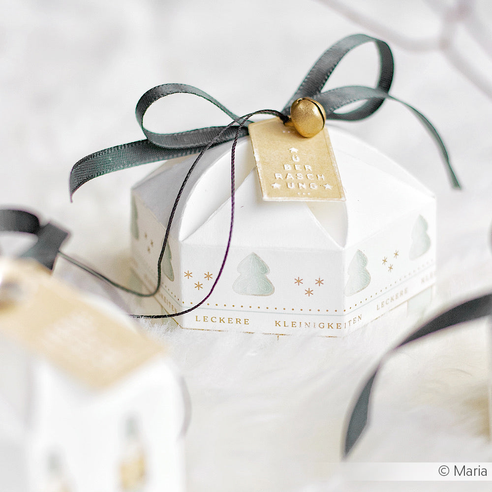 Weiße sechseckige Geschenkschachtel von Alexandra Renke mit schwarzem Band und goldenem Anhänger, mit Weihnachtsbaum- und Sternmotiven - ideal für Ihre Papierprojekte oder um mit Designpapier oder Blockstreifen Bordüre ein festliches Flair zu schaffen.