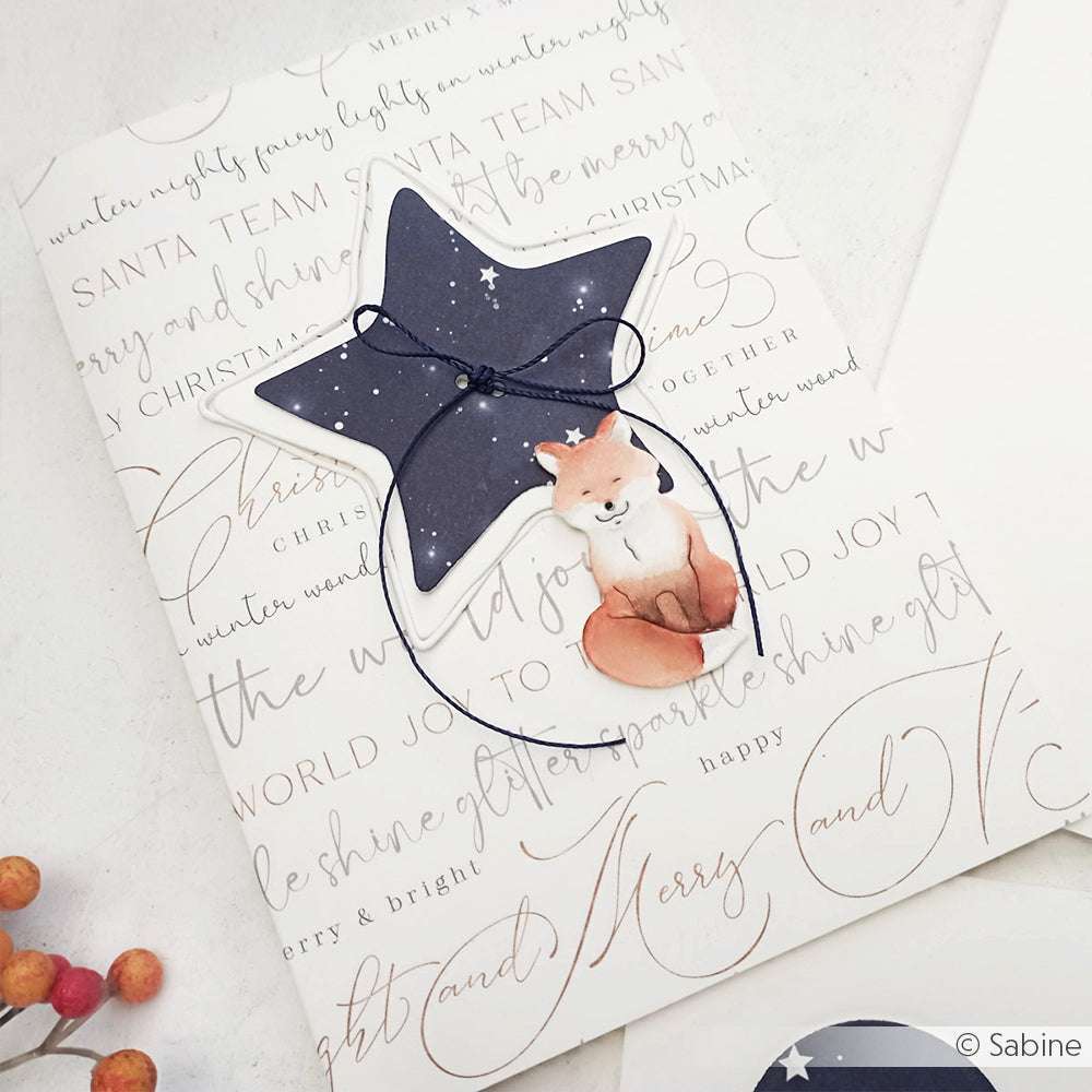 Stern-Ornament mit einem Fuchs unter einem Nachthimmel, gefertigt aus elegantem Designpapier von Alexandra Renke, auf einer festlichen Karte mit einem Text in Schreibschrift.