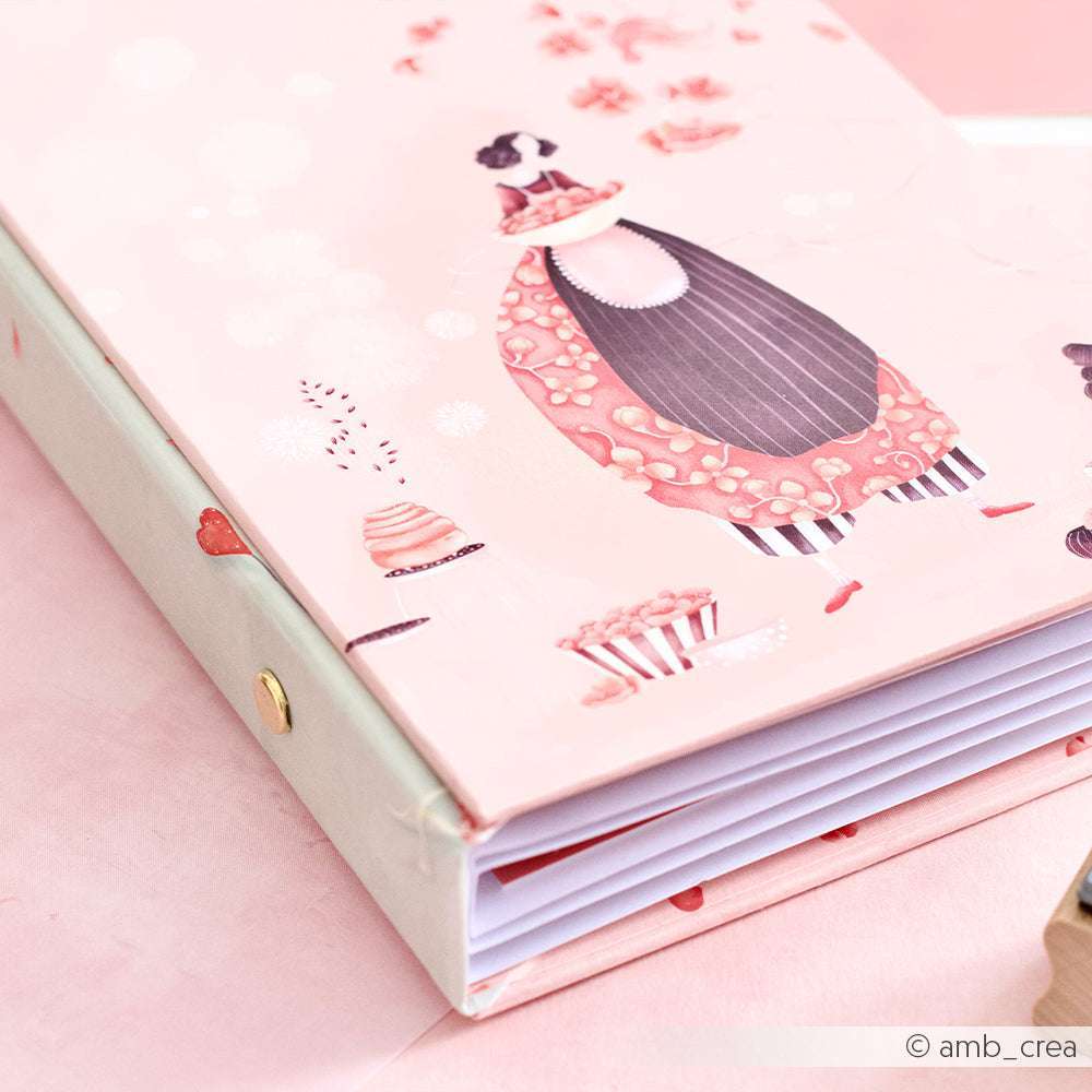 Rosa Notizbuch von Alexandra Renke mit einer skurrilen Illustration einer Frau in einem Kleid und Desserts - ideal für Papierprojekte oder als charmante Ergänzung Ihrer Buchbinderei-Sammlung.