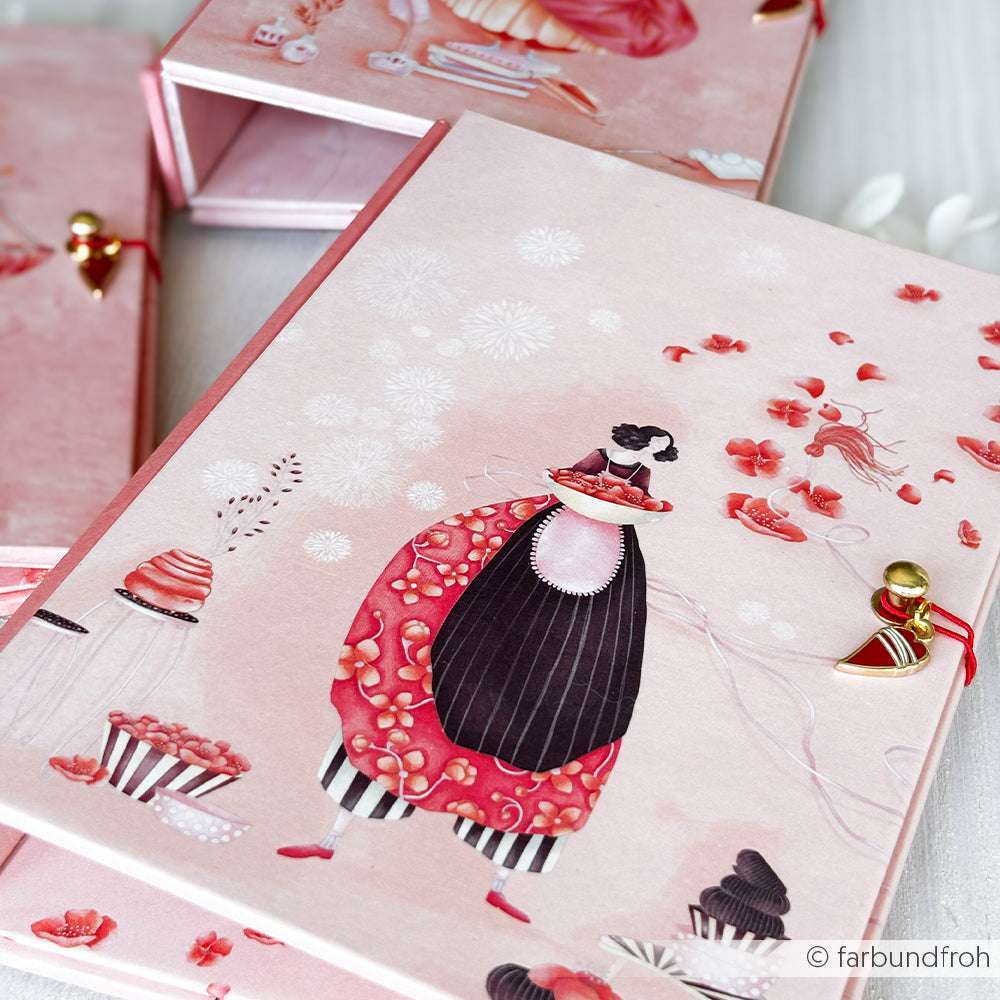 Rosa illustrierte Schachtel mit einer skurrilen Frau in einem roten Kleid, umgeben von Cupcakes und Blumenmustern - ideal für Papierprojekte mit dem Lisas Figurinen Blütenzauber Designpapier von Alexandra Renke.