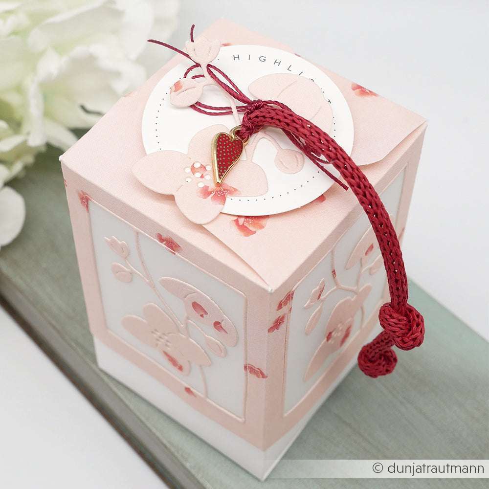 Die zartrosa geblümte Geschenkbox von Alexandra Renke aus Designpapier besticht durch Schmetterlingsakzente und eine rote Kordel, die oben geknotet ist - ideal für stilvolle Papierprojekte.