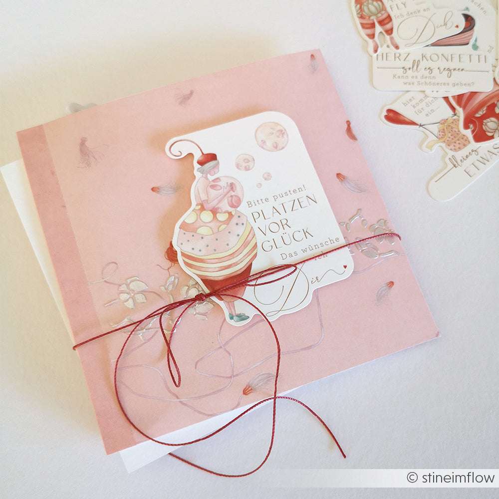 Bezaubernde rosa Grußkarte von Alexandra Renke mit Cupcake-Illustration, Schleife und deutschem Text auf Designpapier - ideal für Papierprojekte oder besondere Anlässe.
