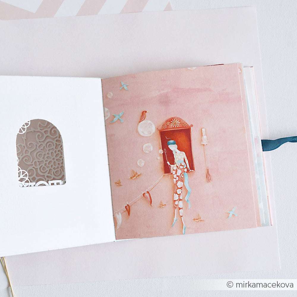 Aufgeschlagener Bildband mit Lisas Figurinen Seifenblasenzauber von Alexandra Renke neben einer Tür, mit pastellfarbenen und dekorativen Designpapier-Elementen auf rosa Hintergrund.