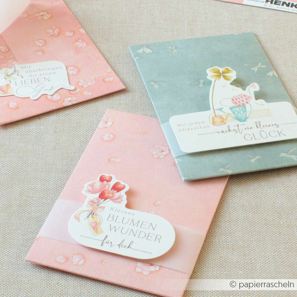 Drei pastellfarbene Blumengrußkarten von Alexandra Renke auf einer hellen Oberfläche, jede mit einem dekorativen deutschen ovalen Etikett - ideal für Papierprojekte oder zum Kombinieren mit Ihrem Lieblingsdesignpapier.