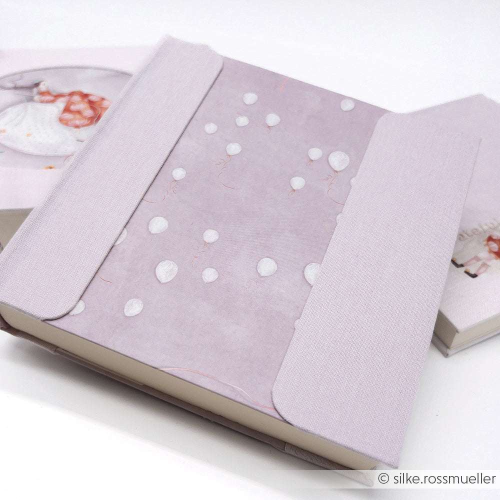 Alexandra Renke lavendelfarbenes Notizbuch mit Ballonmuster und Stoffeinband, ideal für Papierprojekte oder Buchbinderei, teilweise geöffnet auf weißem Hintergrund.