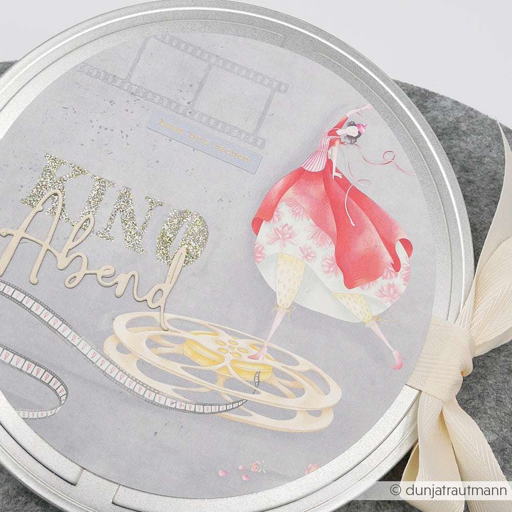 Runde Dose von Alexandra Renke mit dem Motiv einer Filmrolle, dem Text "Kino Abend" und einer Frau in einem roten Kleid - ideal für Papierprojekte oder Fans von Lisas Figurinen Filmzauber.