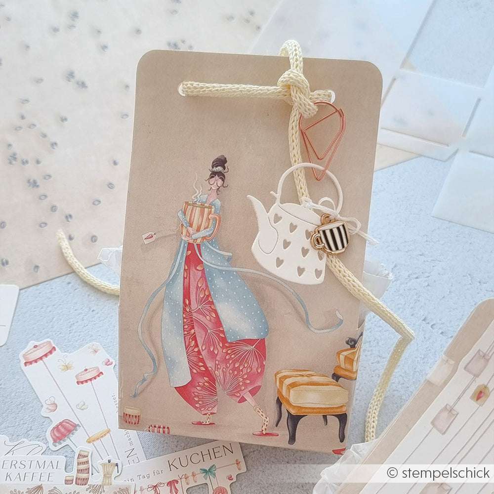 Ein Geschenkanhänger von Alexandra Renke mit einer Frau im Kimono, einem Teekannenanhänger und einer herzförmigen Büroklammer - ideal für Papierprojekte oder als Inspiration für Kreationen der Buchbinderei.